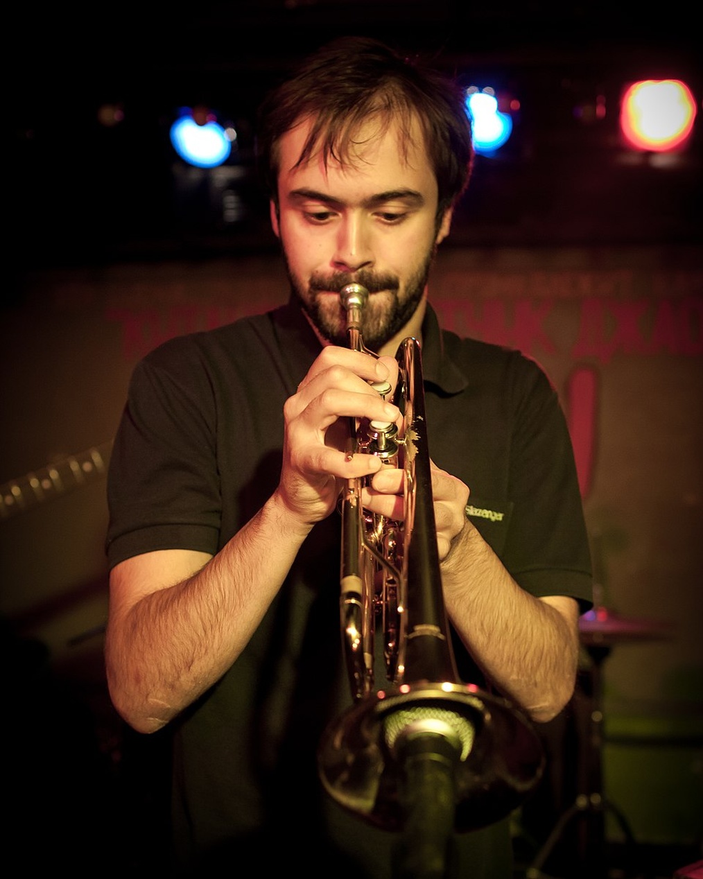 A solo musician plays the trumpet in a dimly lit club, a perfect example of an individual artist who can now connect and create with others globally.