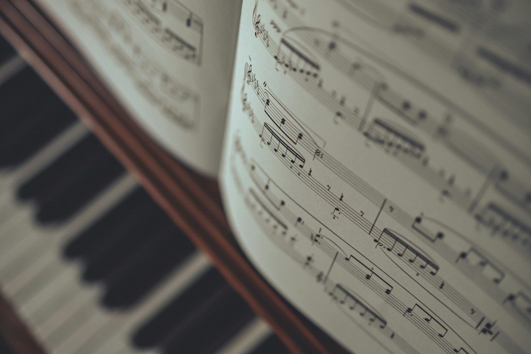 Close-up of piano keys beside open sheet music with musical notation